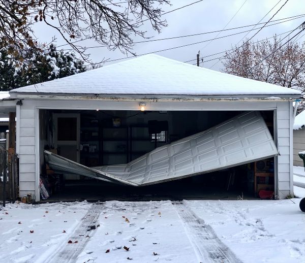 Collapsed garage door panel after heavy snow damage in residential driveway in Calgary, AB