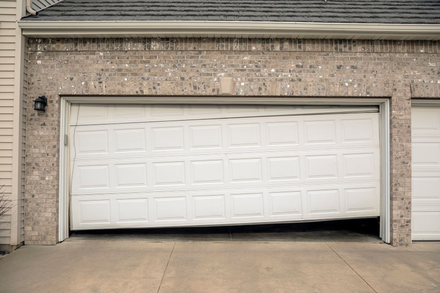 Damaged garage door panel stuck halfway open on residential home in Calgary, AB