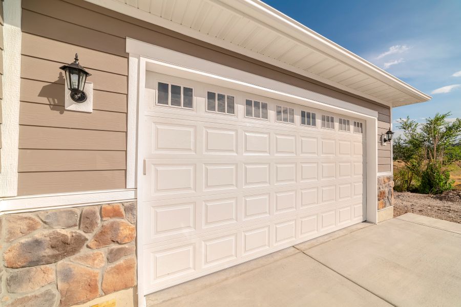 Modern white garage door with window panels on residential exterior in Calgary, AB