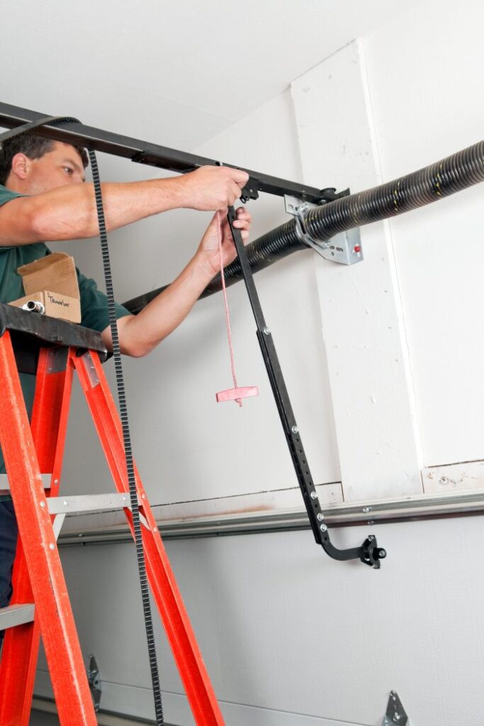 Garage door technician adjusting torsion spring and opener mechanism